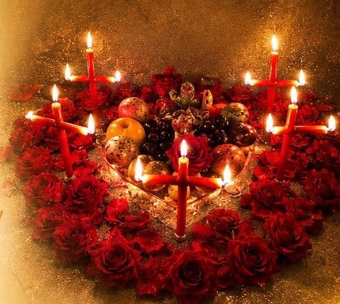 Trabalho amoroso montado em forma de coração, com rosas vermelhas, frutas e velas vermelhas acesas
